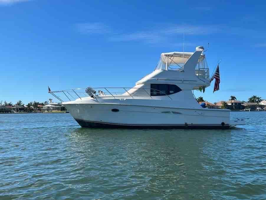 White motor yacht anchored in shallow turquoise water under clear blue sky