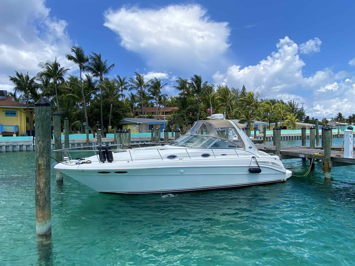 White cabin cruiser boat moored in turquoise water with colorful waterfront buildings and palm trees
